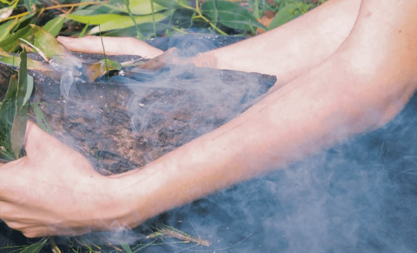 Smoking with gum leaves and arms surrounding the smoke