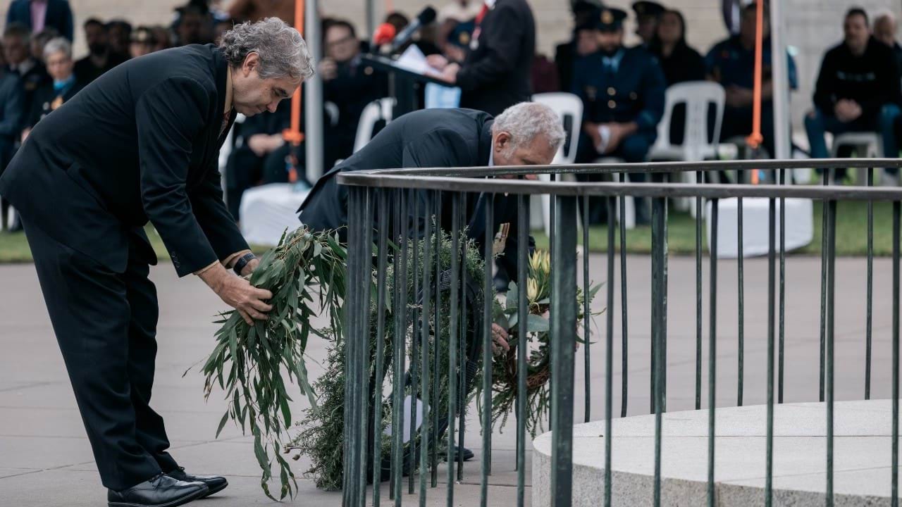 Dr Andrew Peters laying a gum wreath and Sam Halim laying a native wreath at the eternal flame at the Shrine of Remembrance.